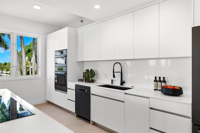 kitchen featuring white cabinets, sink, light hardwood / wood-style flooring, and black appliances