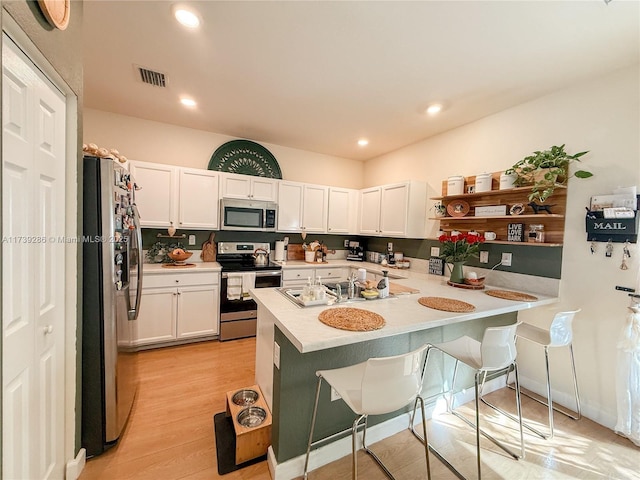 kitchen featuring white cabinetry, appliances with stainless steel finishes, a breakfast bar, and kitchen peninsula