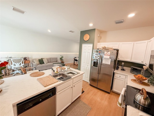 kitchen featuring stainless steel appliances, white cabinetry, sink, and light hardwood / wood-style floors