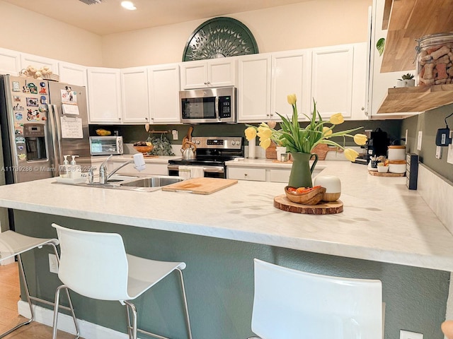 kitchen featuring appliances with stainless steel finishes, sink, white cabinets, and a kitchen bar