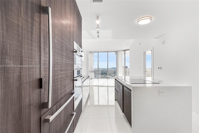 kitchen with refrigerator, light tile patterned floors, a kitchen island, expansive windows, and black electric stovetop