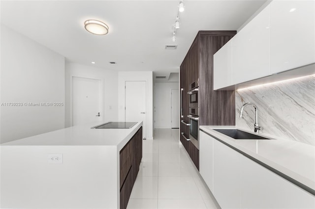 kitchen featuring light tile patterned flooring, sink, white cabinetry, dark brown cabinets, and black electric stovetop