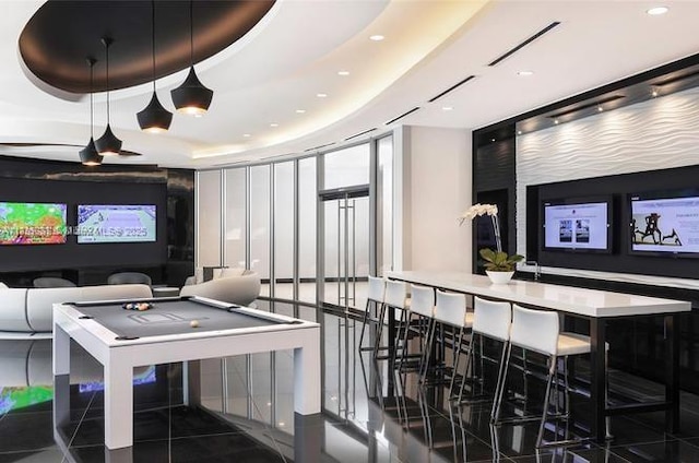 playroom featuring pool table, a raised ceiling, and a wall of windows