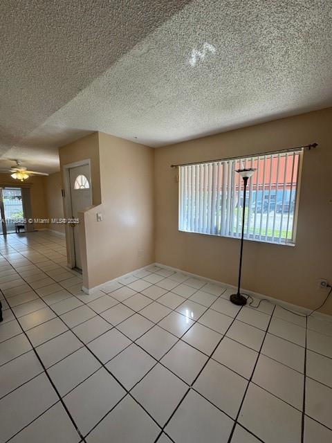 tiled empty room featuring a textured ceiling and ceiling fan