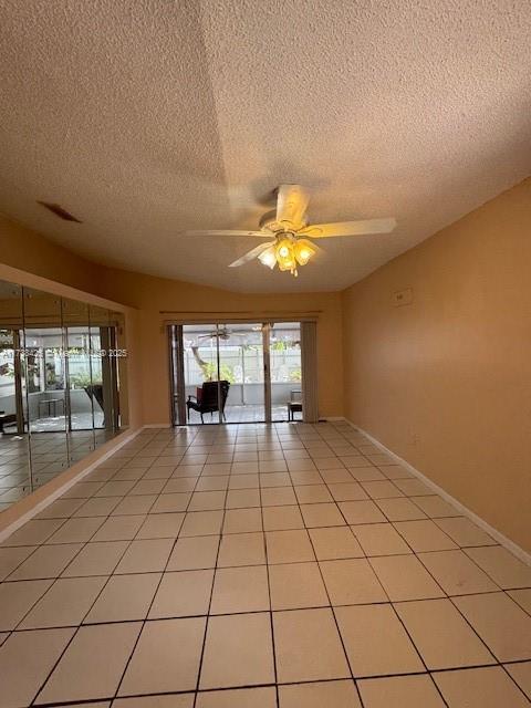 tiled empty room with ceiling fan and a textured ceiling