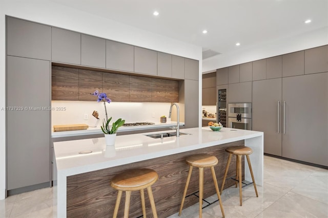 kitchen featuring double oven, sink, a breakfast bar, and a large island with sink