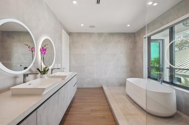 bathroom featuring vanity, hardwood / wood-style floors, tile walls, and a tub