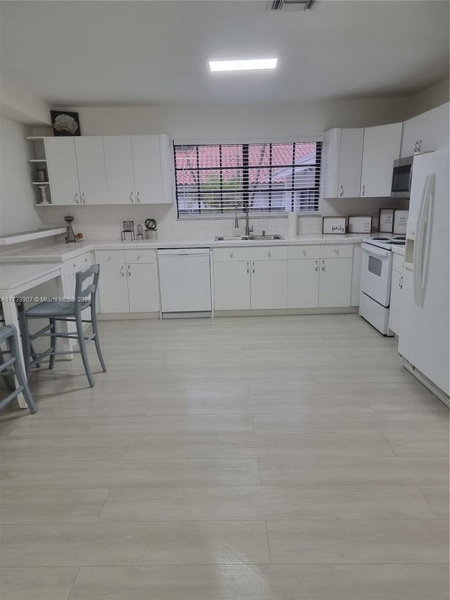 kitchen with sink, white cabinets, white appliances, light hardwood / wood-style floors, and backsplash