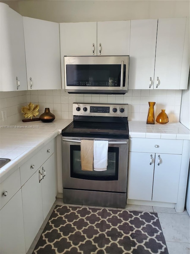 kitchen featuring white cabinetry, appliances with stainless steel finishes, and tasteful backsplash