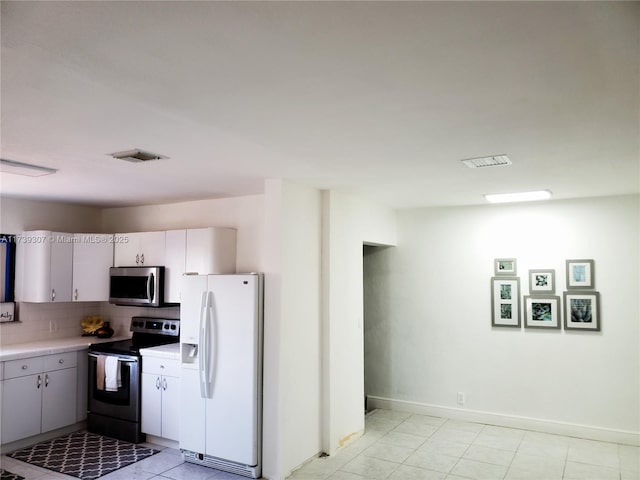 kitchen with stainless steel appliances, tasteful backsplash, light tile patterned floors, and white cabinets