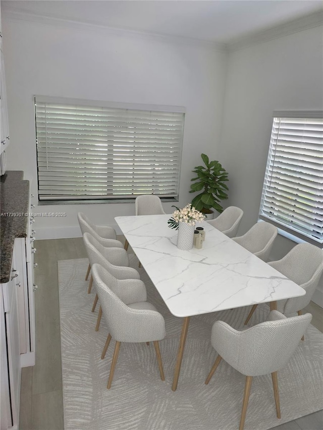 dining space featuring ornamental molding and light hardwood / wood-style floors