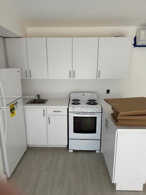 kitchen featuring white cabinetry, sink, white appliances, and light hardwood / wood-style floors