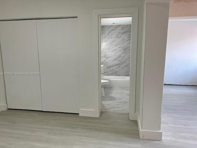 interior space featuring connected bathroom, light hardwood / wood-style flooring, and a closet