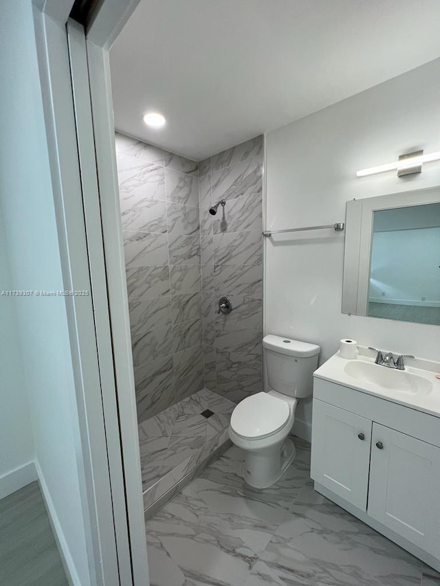 bathroom with vanity, toilet, and a tile shower