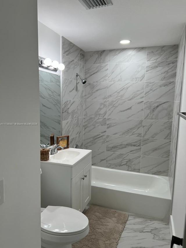 full bathroom with tiled shower / bath, vanity, and toilet