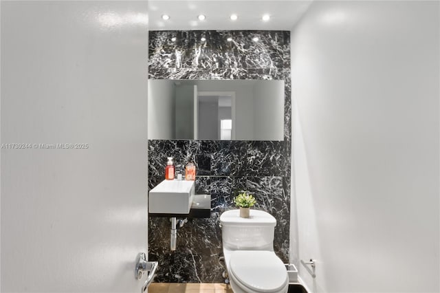 bathroom featuring sink, backsplash, and toilet