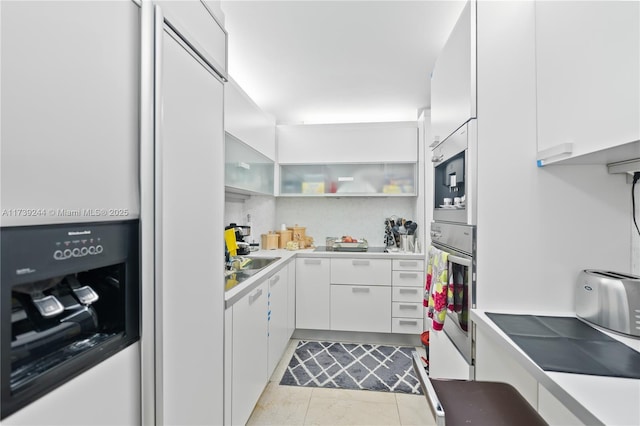 kitchen featuring stainless steel oven, white cabinets, and light tile patterned floors