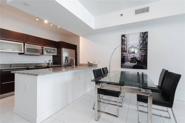 kitchen featuring stainless steel appliances, a kitchen bar, and dark brown cabinets