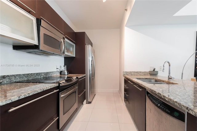 kitchen with sink, appliances with stainless steel finishes, dark brown cabinetry, light stone countertops, and light tile patterned flooring