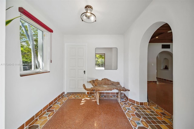 hallway with arched walkways, visible vents, and baseboards