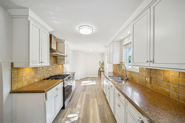 kitchen featuring gas stove, white cabinetry, and a sink