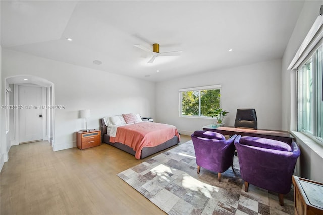 bedroom with arched walkways, ceiling fan, baseboards, and light wood-style floors