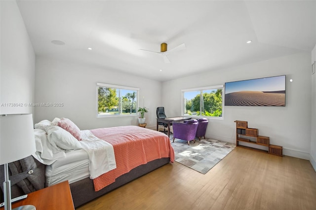 bedroom featuring light wood finished floors, ceiling fan, multiple windows, and baseboards