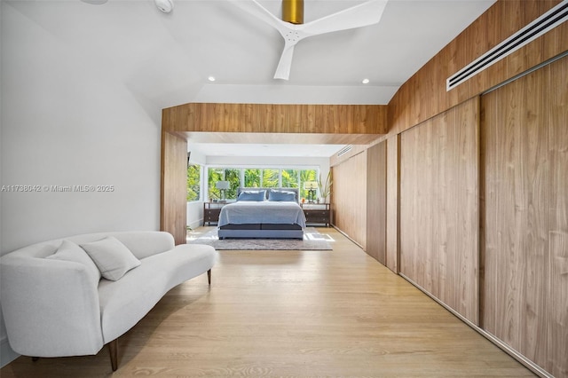 bedroom featuring light wood-type flooring, vaulted ceiling, and wooden walls