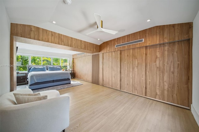 interior space featuring vaulted ceiling, light wood finished floors, wood walls, and a ceiling fan