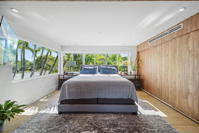 bedroom with wood walls, multiple windows, wood finished floors, and recessed lighting