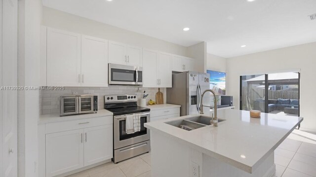 kitchen with a kitchen island with sink, sink, and stainless steel appliances