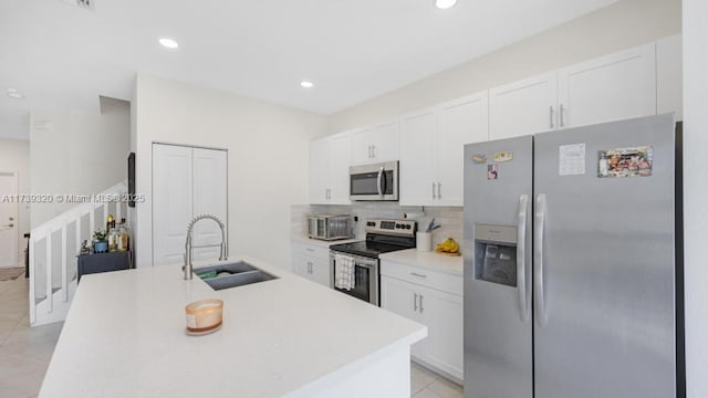 kitchen featuring sink, stainless steel appliances, an island with sink, and white cabinets