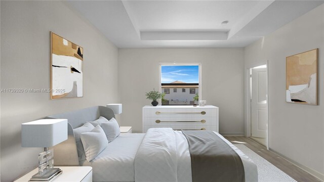 bedroom with a raised ceiling and light hardwood / wood-style flooring