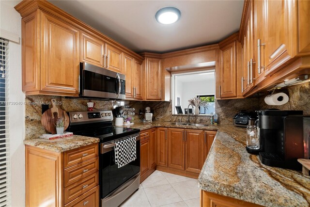 kitchen with appliances with stainless steel finishes, sink, backsplash, light tile patterned floors, and light stone counters