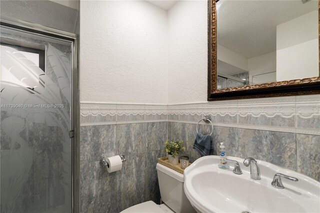 bathroom featuring toilet, sink, and tile walls