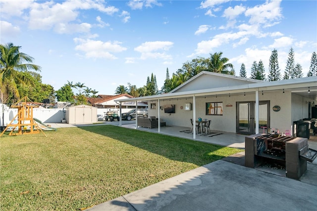 view of yard featuring a patio, a playground, and a storage unit