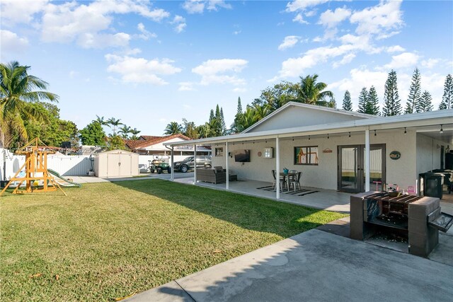 view of yard featuring a patio, a playground, and a storage unit