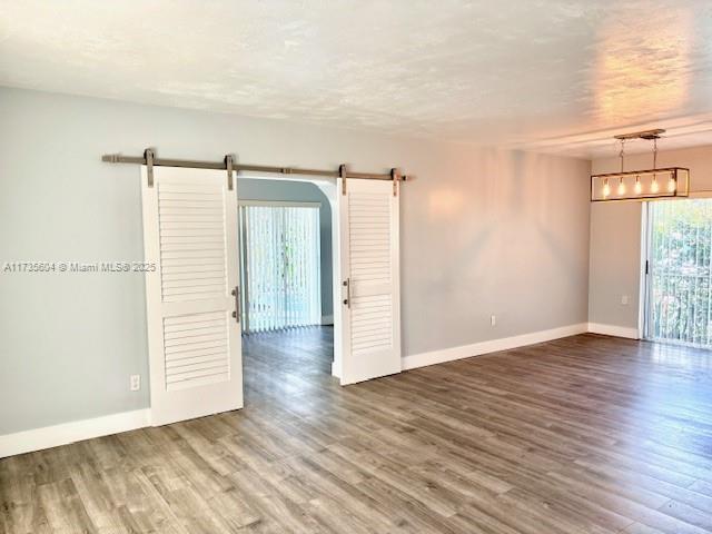 unfurnished room featuring hardwood / wood-style flooring, a barn door, and a notable chandelier