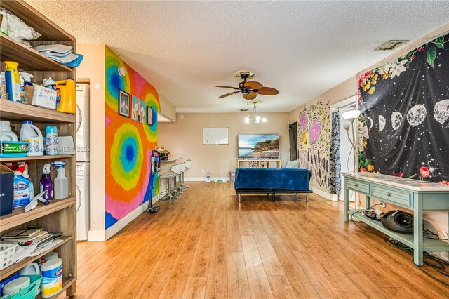 interior space with ceiling fan, light hardwood / wood-style floors, and a textured ceiling