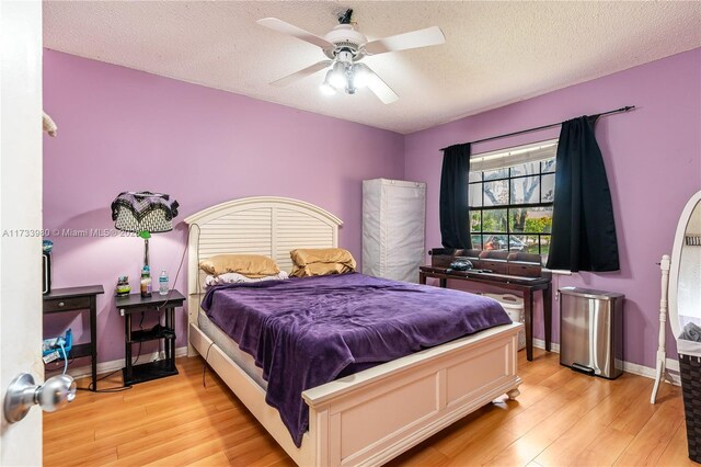 bedroom with ceiling fan, light hardwood / wood-style flooring, and a textured ceiling