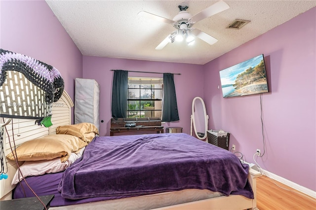 bedroom featuring ceiling fan, hardwood / wood-style flooring, and a textured ceiling