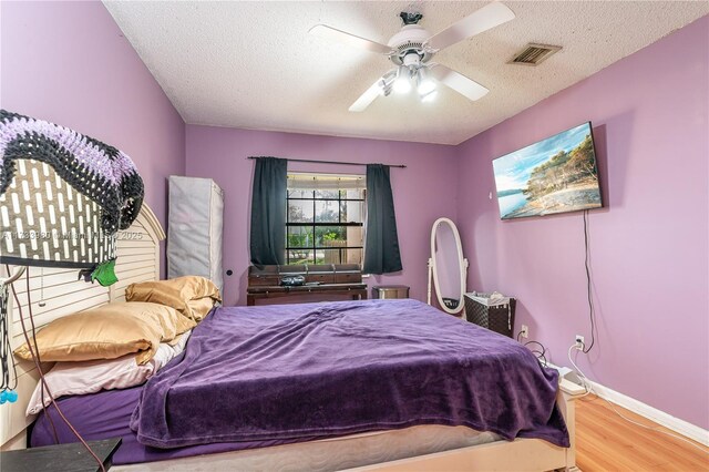 bedroom featuring ceiling fan, hardwood / wood-style flooring, and a textured ceiling