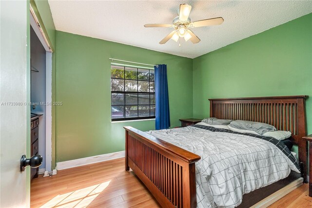 bedroom with ceiling fan, a textured ceiling, and light wood-type flooring