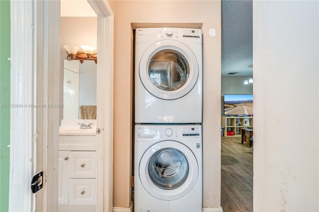 laundry room featuring stacked washer / dryer, sink, and hardwood / wood-style floors