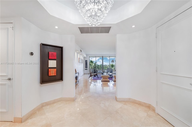 hall featuring a wall of windows, baseboards, visible vents, and a chandelier