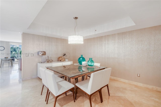 dining room featuring a raised ceiling and baseboards