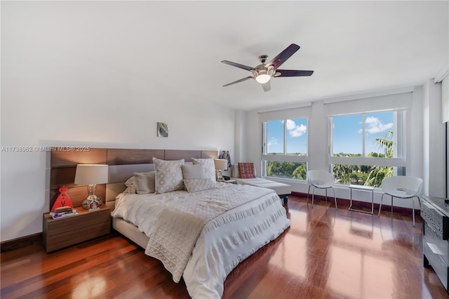 bedroom featuring baseboards, wood finished floors, and a ceiling fan