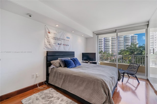 bedroom featuring access to outside, baseboards, and wood finished floors