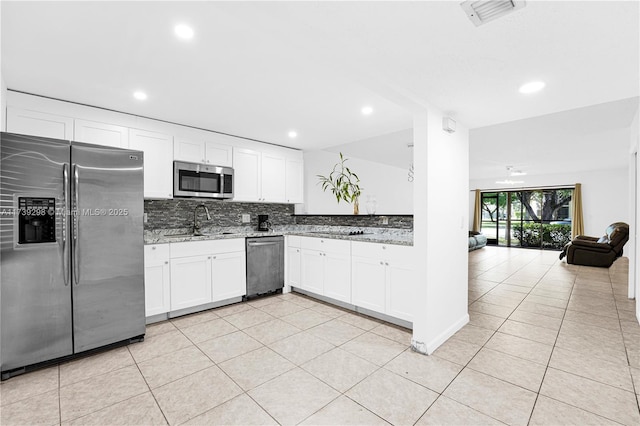 kitchen featuring appliances with stainless steel finishes, tasteful backsplash, white cabinetry, sink, and light stone countertops