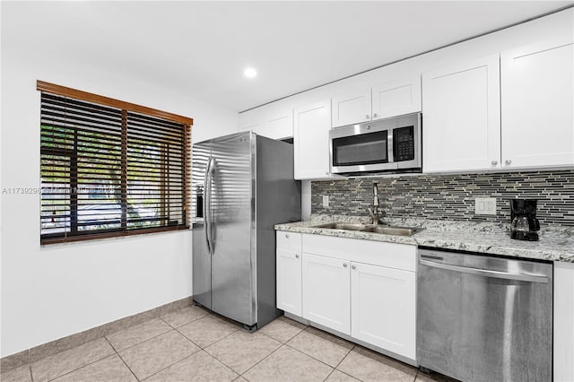 kitchen featuring sink, appliances with stainless steel finishes, light stone countertops, white cabinets, and decorative backsplash